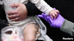 Sherry Andrews, right, holds 13-month-old Jaqi Herrera’s hand after administering the first MMR vaccine dose to Herrera at the City of Lubbock Health Department in Lubbock, Texas, Feb. 27, 2025. 