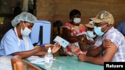 FILE PHOTO: A man receives a certificate after being vaccinated against the coronavirus disease (COVID-19) at Wilkins Hospital in Harare, Zimbabwe, March 24, 2021. REUTERS/Philimon Bulawayo/File Photo