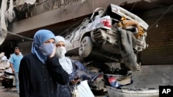 Mujeres libanesas pasan cerca de autos destruidos, en el lugar del ataque aéreo israelí del jueves, en Beirut, Líbano, el viernes 11 de octubre de 2024. AP