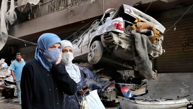 Mujeres libanesas pasan cerca de autos destruidos, en el lugar del ataque aéreo israelí del jueves, en Beirut, Líbano, el viernes 11 de octubre de 2024. AP