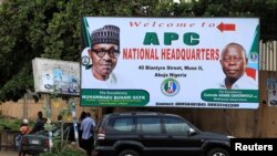 People stand near a sign for the All Progressive Congress (APC) national headquarters in Abuja, Nigeria, July 5, 2018. 