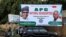 People stand near a sign for the All Progressive Congress (APC) national headquarters in Abuja, Nigeria, July 5, 2018. 