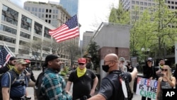 FILE - Members of a far-right group argue with a Black counterprotester during a rally in downtown Seattle, Washington, May 1, 2020.