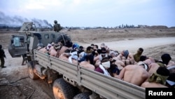 Israeli soldiers stand by a truck packed with shirtless Palestinian detainees, amid the ongoing conflict between Israel and the Palestinian Islamist group Hamas, in the Gaza Strip Dec. 8, 2023. 