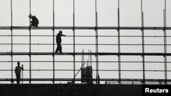 Laborers work on scaffolding at a residential construction site in Hefei, Anhui province, China. 
