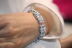FILE - "Jane Doe 15," who accuses the late financier Jeffrey Epstein of sexually abusing her when she was a teenager, wears a bracelet that reads "Epstein didn't kill himself" at a news conference in Los Angeles, Nov. 18, 2019.