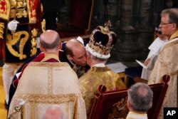 Pangeran William mencium ayahnya Raja Charles III, saat upacara penobatannya di Westminster Abbey, London, Sabtu 6 Mei 2023. (Foto:Yui Mok via REUTERS)