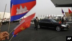 Cambodian students gather to welcome Chinese President Hu Jiantao as seen a car is escorted by bodyguards during his arrival at Phnom Penh International Airport, Phnom Penh, Cambodia, Friday, March 30, 2012. Hu on Friday arrived Phnom Penh on his four-day