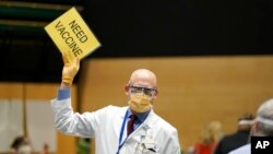 FILE - Dr. John Corman, the chief clinical officer for Virginia Mason Franciscan Health, holds a sign that reads "Need Vaccine" to signal workers to bring him more doses of the Pfizer vaccine for COVID-19, Jan. 24, 2021.