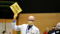 FILE - Dr. John Corman, the chief clinical officer for Virginia Mason Franciscan Health, holds a sign that reads "Need Vaccine" to signal workers to bring him more doses of the Pfizer vaccine for COVID-19, Jan. 24, 2021.