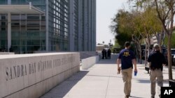 FILE - Federal law enforcement personnel walk past the Sandra Day O'Connor Federal Courthouse, Sept. 15, 2020, in Phoenix.