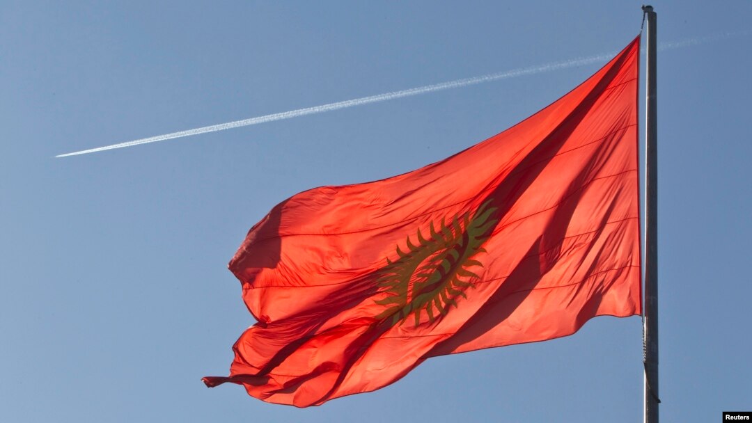 An airplane trace is seen behind a Kyrgyzstan national flag fluttering in a central square in the country's capital Bishkek.