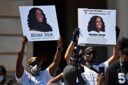 FILE - Signs are held up showing Breonna Taylor during a rally in her honor on the steps of the Kentucky State Capitol in Frankfort, Ky., June 25, 2020.