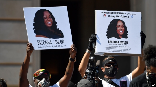 FILE - Signs are held up showing Breonna Taylor during a rally in her honor on the steps of the Kentucky State Capitol in Frankfort, Ky., June 25, 2020.