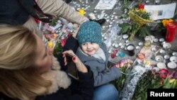 A woman looks at her daughter on the Place de la Bourse in central Brussels, on March 23, 2016 as people gather to observe a minute of silence in memory of the victims of the Brussels airport and metro bombings.