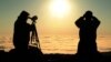 Dos personas observan a través de binoculares el tránsito de Venus frente al sol, en las montañas Cadillac, en el parque nacional Acadia, en Maine, Estados Unidos.