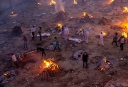 FILE - People wait to cremate victims who died due to the coronavirus disease, at a crematorium ground in New Delhi, India, April 23, 2021.