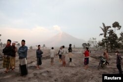 Warga desa berdiri di area yang tertutup abu vulkanik saat Gunung Semeru meletus terlihat dari kawasan Sumberwuluh, Lumajang, provinsi Jawa Timur, 5 Desember 2022. (Antara Foto/Umarul Faruq/via REUTERS)