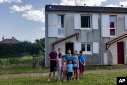 Olga Lopatkina and her children pose for a photo in front of their house in Loue, western France, Saturday, July 2, 2022. (AP Photo/Jeremias Gonzalez)