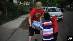 Michael Grunke help his neighbor's children with a case of water during his neighborhood watch activity, which started after the police custody death of George Floyd sparked unrest, June 2, 2020, in Minneapolis, Minn.