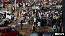 Warga berkumpul di lokasi ledakan bom di terminal bus di Nyayan, Abuja, Nigeria (14/4).