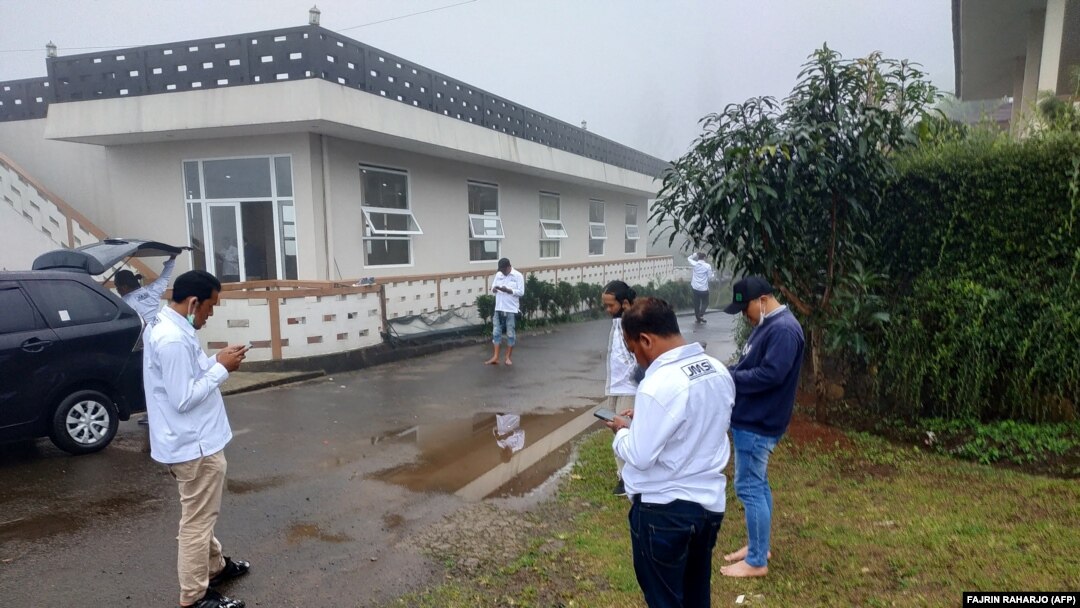 Des riverains vérifient leurs téléphones alors qu'ils se rassemblent à l'extérieur de Cisarua, Bogor, le 14 janvier 2022, peu après le tremblement de terre de magnitude 6,6 qui a frappé l'île de Java, en Indonésie. 