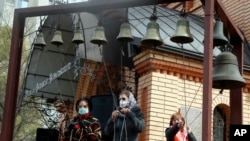 Women wearing face masks to protect against coronavirus ring the church bells at a memorial of the Chernobyl tragedy victims in capital Kyiv, Ukraine, April 26, 2020.