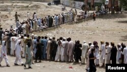 People, who fled the military offensive against Pakistani militants in North Waziristan, line up to receive food supply from the army in Bannu, in Pakistan's Khyber-Pakhtunkhwa province, June 25, 2014.