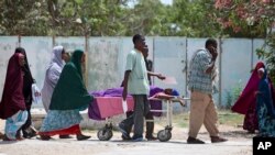 Para kerabat membantu seorang perempuan yang terluka dalam serangan mortir di istana presiden, Mogadishu, Somalia (26/2). (AP/Farah Abdi Warsameh)