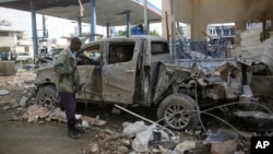 Un agent de la sécurité en Somalie fouille l'épave d'un camion devant l'hôtel Nasahablood après une attaque revendiquée par le groupe islamique extrémiste al-Shabab, à Mogadiscio, Somalie, 26 juin 2016. (AP Photo / Farah Abdi Warsameh)
