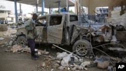 A Somali security man looks at the wreckage of a truck near the Nasahablood hotel in Mogadishu, Somalia, June 26, 2016. The Islamic extremist group al-Shabab claimed responsibility for the damage, inflicted in an attack the day before.