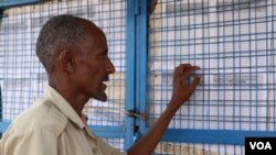 Somali man in Kakuma refugee camp checks the board to see if his name is on the list for an interview with the International Organization for Migration (IOM) for potential resettlement to the U.S. Kakuma, Kenya. February 6, 2017. (J.Craig / VOA)