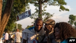 Supporters of the Union for Democracy and Social Progress and Democratic Republic of Congo President Felix Tshisekedi listen to a radio as he gathers with others near the party head quarter in Kinshasa on Dec. 6, 2020 to hear a speech from the President. 