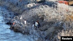 Un grupo de migrantes se encuentra en el borde del Río Grande en Eagle Pass, Texas, EEUU, el 3 de febrero de 2024.