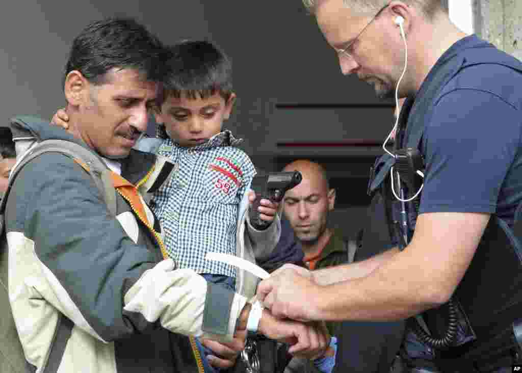 A policeman puts a registration marker to the hand of a man who holds a boy at the rail station in Freilassing, southern Germany, at the border to Austria.