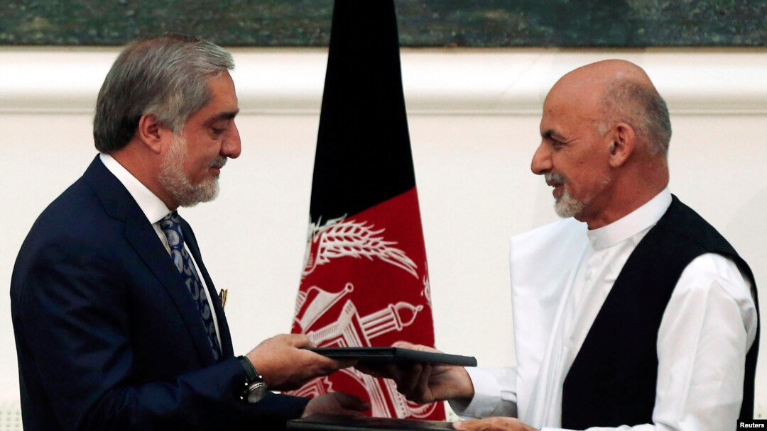 Calon presiden Afghanistan Abdullah Abdullah (kiri) dan Ashraf Ghani bertukar perjanjian yang ditandatangani untuk pembagian kekuasaan di Kabul, 21 September 2014. 