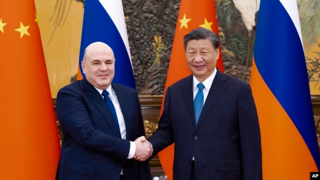 FILE - In this photo released by Xinhua News Agency, visiting Russian Prime Minister Mikhail Mishustin, left, shakes hands with Chinese President Xi Jinping before their talks in Beijing on Dec. 20, 2023.