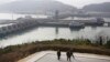 North Korean men walk with the West Sea Barrage in the background in Nampo, North Korea, Feb. 2, 2019.