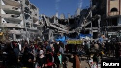 Palestinians shop in an open-air market near the ruins of houses and buildings destroyed in Israeli strikes during the conflict, amid a temporary truce between Hamas and Israel, in Nuseirat refugee camp in the central Gaza Strip November 30, 2023.