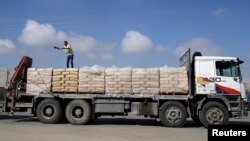 FILE - A Palestinian worker stands atop a truck loaded with bags of cement after entering Gaza, at the Kerem Shalom crossing in Rafah in the southern Gaza Strip, Nov. 10, 2014.