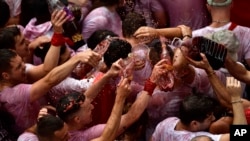 People celebrate during the launch of the 'Chupinazo' rocket, to mark the official opening of the 2022 San Fermin festival in Pamplona, Spain on July 6, 2022. (AP Photo/Alvaro Barrientos)