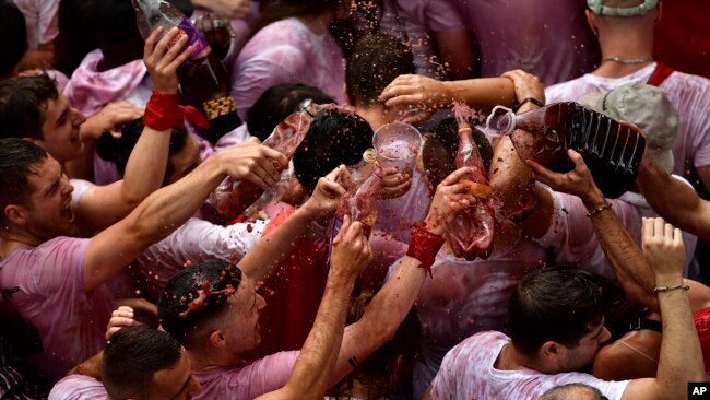 People celebrate during the launch of the 'Chupinazo' rocket, to mark the official opening of the 2022 San Fermin festival in Pamplona, Spain on July 6, 2022. (AP Photo/Alvaro Barrientos)