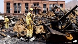 Los Angeles County firefighter Darrick Woolever examines metal that needs to be removed after a fire, June 2, 2008, at the Universal Studios Hollywood back lot.