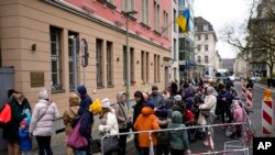 ARCHIVO - Personas de Ucrania, la mayoría de ellos refugiados que huyen de la guerra, hacen fila frente al departamento consular de la embajada ucraniana en Berlín, Alemania, el 6 de abril de 2022.