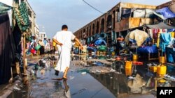 Un homme saute par-dessus une flaque d'eau dans le marché de la capitale inondé après une tempête le 2 avril 2019 à Nouakchott. (Photo by Carmen Abd Ali / AFP)