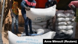 Des ouvriers transportent l'aide fournie par le PAM pour la distribuer à Pissila, au Burkina Faso, le 24 janvier 2020.