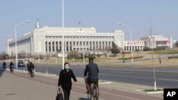 People walk past the building of the Presidium of the Supreme People's Assembly in Pyongyang, Thursday, April 9, 2020.