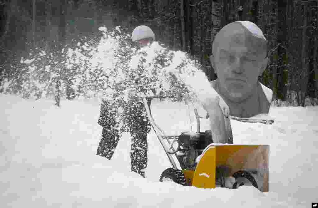 A worker clears snow at the Lenin Hut Museum in a forest near Razliv Lake, outside St.Petersburg, Russia.