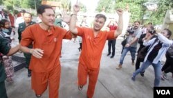 Ny Sokha, left, and Nay Vanda, right, two senior human rights monitoring officers from ADHOC, are escorted by police to the Supreme Court, Phnom Penh, Cambodia, November 23, 2016. (Leng Len/VOA Khmer