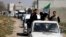 FILE - Free Syrian Army fighters head a convoy of vehicles carrying humanitarian supplies as they enter Damascus, March 20, 2014.